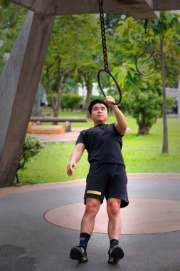 Genç adam parkta çemberle egzersiz yapıyor.