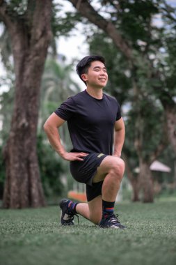 Asyalı genç adam parkta egzersiz yapıyor.