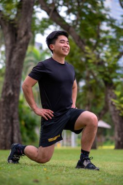 Asyalı genç adam parkta egzersiz yapıyor.