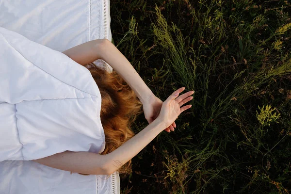 Sarışın bir kız yeşil bir tarlada bir yatakta yatıyor. Yüzü kapalı. Yukarıdan bak. Günaydın.