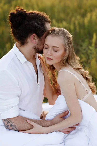 Adam sabah açık havada sarışın kızını yatakta öpüyor.