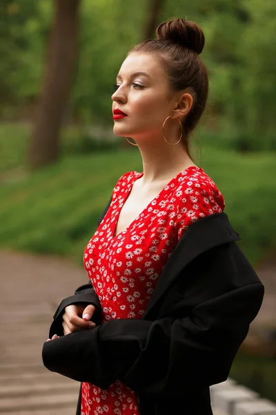 Dívka Červených Šatech Bunda Zeleném Rozmazaném Pozadí Hlavu Natočenou Strany — Stock fotografie