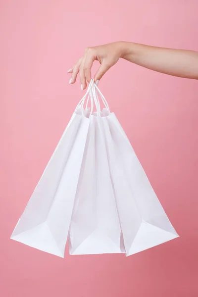 white paper bags in the girl\'s hand on a pink studio background