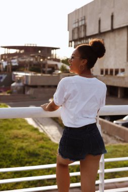 Koyu tenli kız yazın akşamları kentte durur.