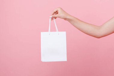 Elinde pembe bir arka planda logonun altında beyaz bir çanta var.