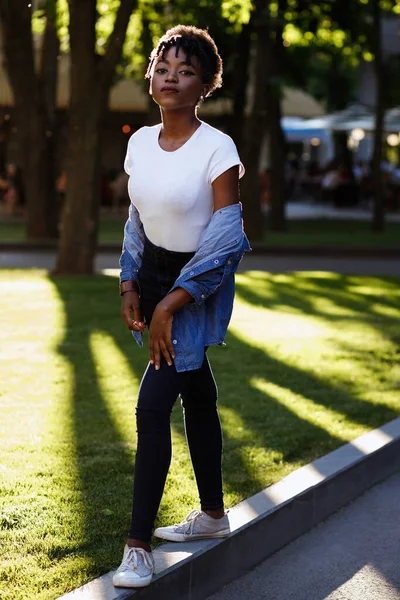 Black girl walks alone in the park in the summer