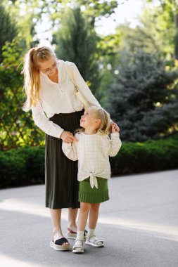 Anne ve kızı yazın parkta yürüyüşe çıkıyorlar.