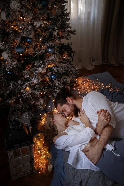 man and woman in bed near Christmas tree