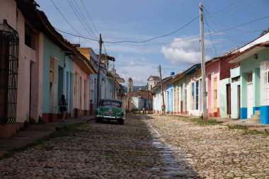 Trinidad, Küba - 10 Ekim 2017: Renkli sokaklar ve Trinidad 'ın geleneksel evleri ve güneşli bir günde park edilmiş yeşil eski bir Küba arabası. Seyahat, turizm bağlamında