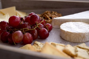 Üzüm, fındık ve ekmekle servis edilen peynir tabağı. Peynirin yan görünüşü hayat dolu