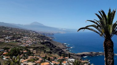 Arka planda Teide volkanı olan güzel Tenerife kuzey kıyısı. Tenerife 'nin panoramik manzaralı turistik kuzey kıyısı, yamaçlardaki köyler ve plantasyonlar
