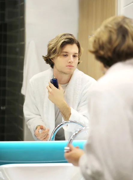 young man looking in the mirror,combing his hair,looking at problems on face