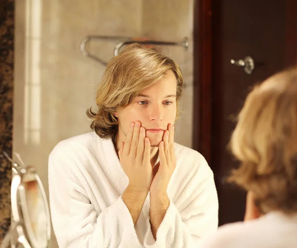 young man looking in the mirror,combing his hair,looking at problems on face