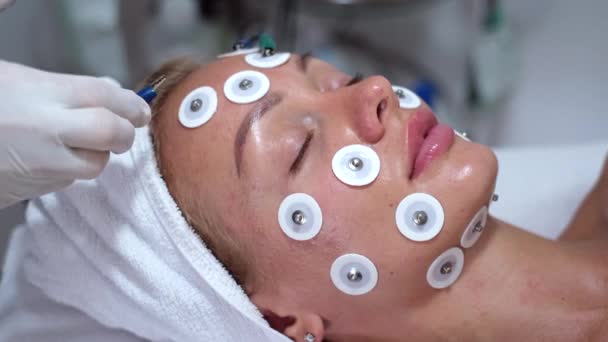 美容师的手在躺在床上的女性病人的脸上做肌萎缩 面部整容的概念和皮肤颜色的恢复 美容和专业面部皮肤护理 — 图库视频影像