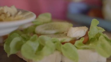 Yakın çekim aşçı tavuk ve sebzeli sandviç yapıyor.  