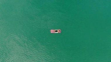 Denizde şişme yatakta mayo giymiş bir kız. Havadan üst görünüm  