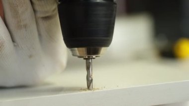 Tahta yonga mobilya yapma süreci. Kesme tahtaları. Kenarları hizala. Tahtada delikler açıyorum. Eldivenli bir adam fabrikada mobilya yapıyor, yakın çekim. Çalışma süreci.          