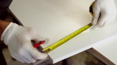 Tahta yonga mobilya yapma süreci. Kesme tahtaları. Kenarları hizala. Tahtada delikler açıyorum. Eldivenli bir adam fabrikada mobilya yapıyor, yakın çekim. Çalışma süreci.          