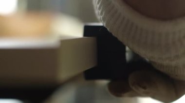 Tahta yonga mobilya yapma süreci. Kesme tahtaları. Kenarları hizala. Tahtada delikler açıyorum. Eldivenli bir adam fabrikada mobilya yapıyor, yakın çekim. Çalışma süreci.          