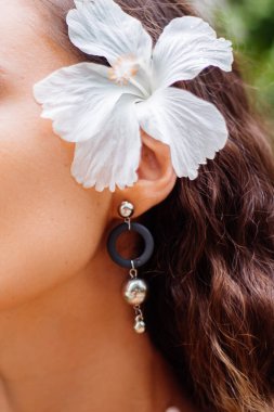 Bronzlaşmış Avrupalı bir kadının açık hava portresi. Kısa saçlı, yuvarlak, palmiye yapraklı, tropikal arka planı olan bir kadın..