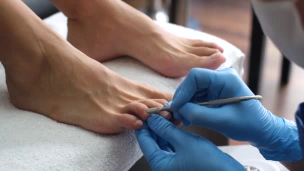 Pediküre. Salon Pediküre zu Hause. Fußpflege und Nagelpflege. Der Prozess der professionellen Pediküre. Meister in blauen Handschuhen machen Pediküre mit Maniküre-Maschine.    