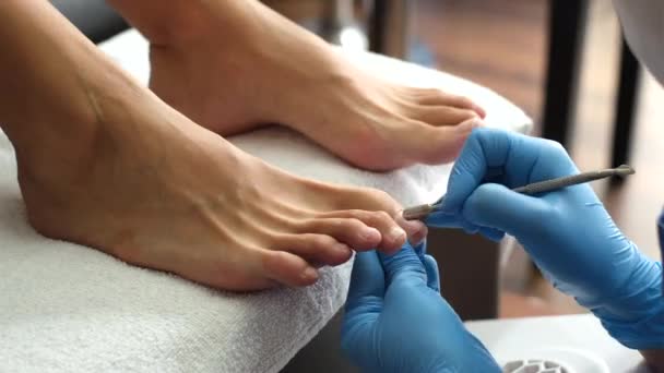 Pediküre. Salon Pediküre zu Hause. Fußpflege und Nagelpflege. Der Prozess der professionellen Pediküre. Meister in blauen Handschuhen machen Pediküre mit Maniküre-Maschine.    