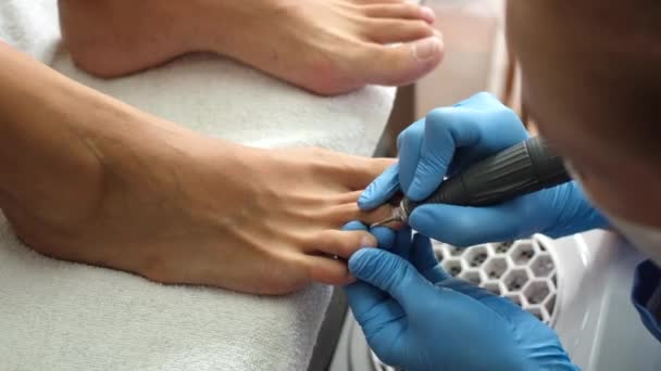 Pediküre. Salon Pediküre zu Hause. Fußpflege und Nagelpflege. Der Prozess der professionellen Pediküre. Meister in blauen Handschuhen machen Pediküre mit Maniküre-Maschine.        