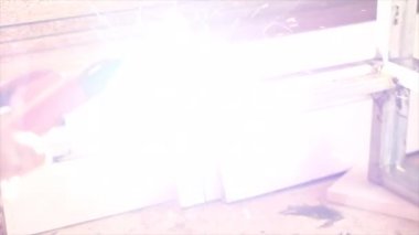 Fabrikada koruyucu maskeli bir işçi. Kaynak çelik profili. Bağlama yayı. Ateş, çalışmadan dolayı parıltı üretir