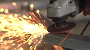 İşçiler çeliği keser. Manüel metal testeresi, demir öğütürken kıvılcımlar. Açı öğütücü, parlak kıvılcımlar yanlara doğru uçar.   