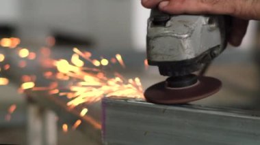 İşçiler çeliği keser. Manüel metal testeresi, demir öğütürken kıvılcımlar. Açı öğütücü, parlak kıvılcımlar yanlara doğru uçar.   