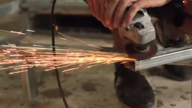 İşçiler çeliği keser. Manüel metal testeresi, demir öğütürken kıvılcımlar. Açı öğütücü, parlak kıvılcımlar yanlara doğru uçar.   