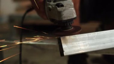 İşçiler çeliği keser. Manüel metal testeresi, demir öğütürken kıvılcımlar. Açı öğütücü, parlak kıvılcımlar yanlara doğru uçar.   