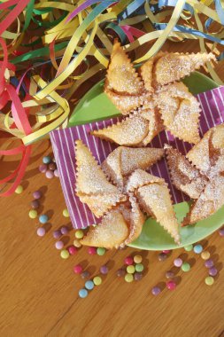 Geleneksel karnaval pastası, chiacchere ya da crostoli, bugie, ahşap arka planda oyuncak bir yel değirmeni şeklinde sansür.