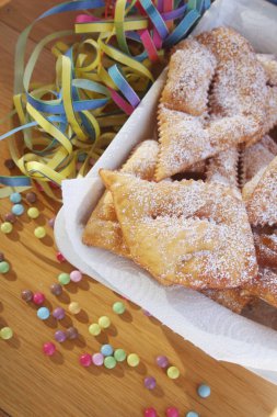 İtalyan karnaval pastası. Geleneksel karnaval pastası, chiacchere veya crostoli, bugie, ahşap arka planda renkli süslemeleri olan cenci
