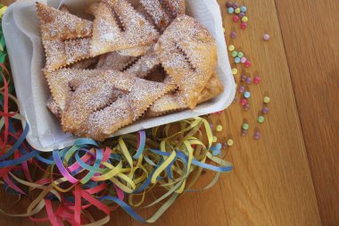 İtalyan karnaval pastası. Geleneksel karnaval pastası, chiacchere veya crostoli, bugie, ahşap arka planda renkli süslemeleri olan cenci