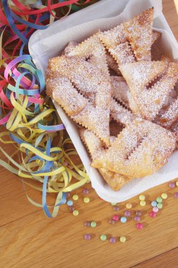 İtalyan karnaval pastası. Geleneksel karnaval pastası, chiacchere veya crostoli, bugie, ahşap arka planda renkli süslemeleri olan cenci