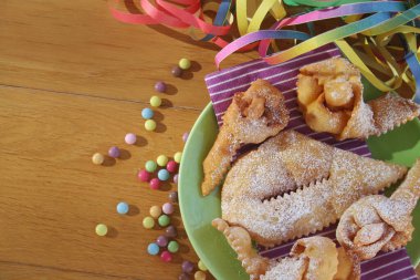 İtalyan karnaval pastası. Geleneksel karnaval pastası, chiacchere veya crostoli, bugie, ahşap arka planda renkli süslemeleri olan cenci