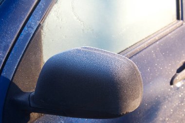 Mavi araba kış mevsiminde donla kaplı. Seçici odak noktasında arabanın yan görünümü.