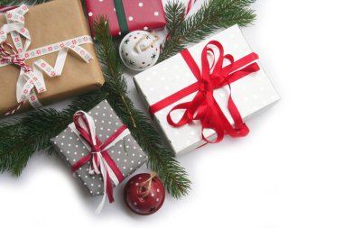 Beyaz arka planda yeşil çam dalları ve dekorasyonlarla izole edilmiş Noel hediyesi kutuları.