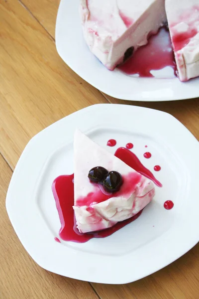 Cheesecake with sour cherries and sauce on a plate on wooden table. Sour cherry cheesecake on a plate