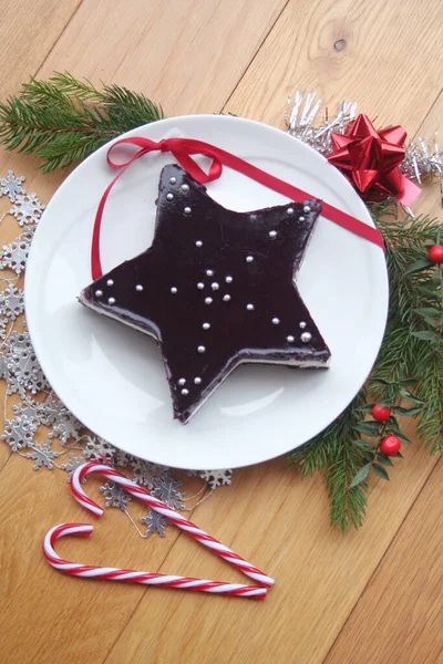 圣诞甜点自制芝士蛋糕 形状像一颗星 放在木制桌子上的盘子里 上面有装饰品和松枝 — 图库照片