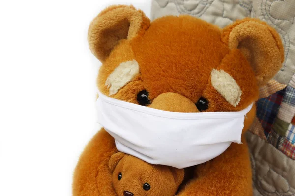 Brown teddy bear with protective medical mask made of fabric. Toy bear with mask for Covid-19 on white background