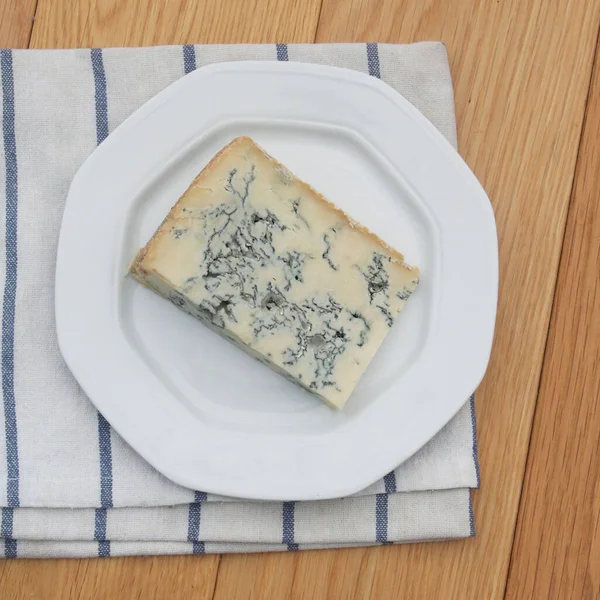 ゴルゴンゾーラチーズは板の上で木のテーブルの上でスライスする ブルーチーズスライス — ストック写真
