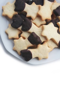 Beyaz arka planda izole bir tabakta kayan yıldız şeklinde çikolata kaplı tereyağlı kurabiyeler. Noel kurabiyeleri