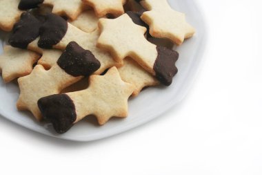 Beyaz arka planda izole bir tabakta kayan yıldız şeklinde çikolata kaplı tereyağlı kurabiyeler. Noel kurabiyeleri