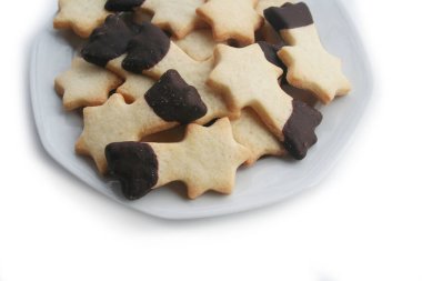 Beyaz arka planda izole bir tabakta kayan yıldız şeklinde çikolata kaplı tereyağlı kurabiyeler. Noel kurabiyeleri