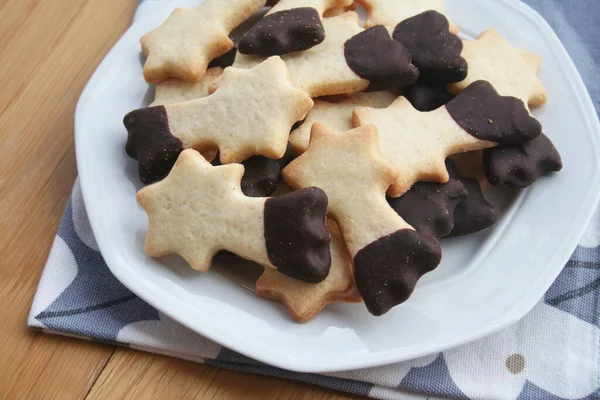 バタークッキーは 木製の背景にプレート上の落下星の形をしたチョコレートで釉 クリスマスクッキー — ストック写真