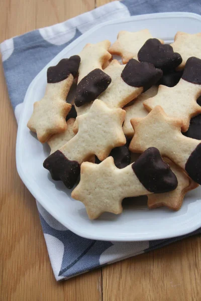 バタークッキーは 木製の背景にプレート上の落下星の形をしたチョコレートで釉 クリスマスクッキー — ストック写真