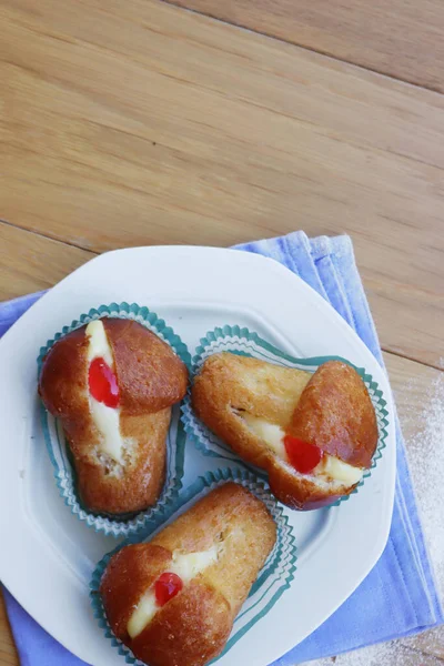 Geleneksel İtalyan tatlısının adı Bab with Rum. Tahta masadaki kremayla dolu. Napoli çöreği. 