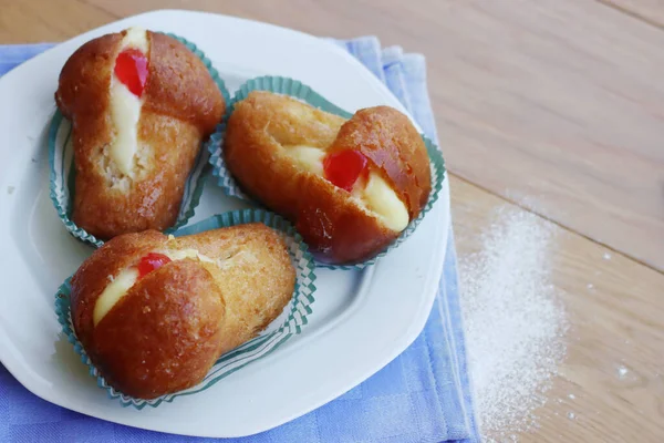 Geleneksel İtalyan tatlısının adı Bab with Rum. Tahta masadaki kremayla dolu. Napoli çöreği. 